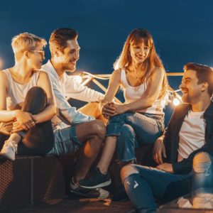 Gruppo di amici che parlano e godono si una serata all'aperto sul tetto.