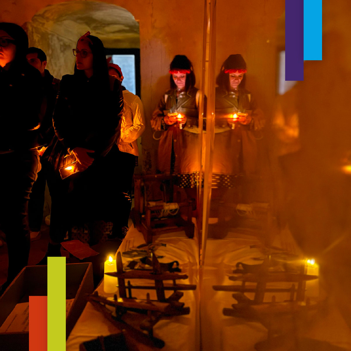 Persone in una stanza antica, illuminata solo da piccole candele. Alcuni tengono candele in mano, altri osservano oggetti esposti. L’atmosfera è raccolta e suggestiva.