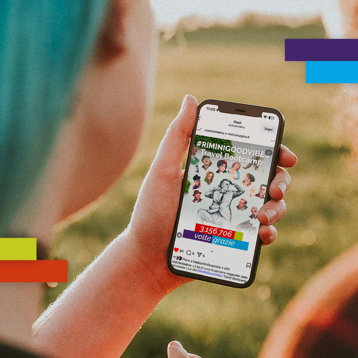Persona guarda uno smartphone con il post "#RiminiGoodVibes Travel Bootcamp" che mostra volti sorridenti, collage grafico e numero di visualizzazioni totali (3.156.706). Lo sfondo è un prato verde.